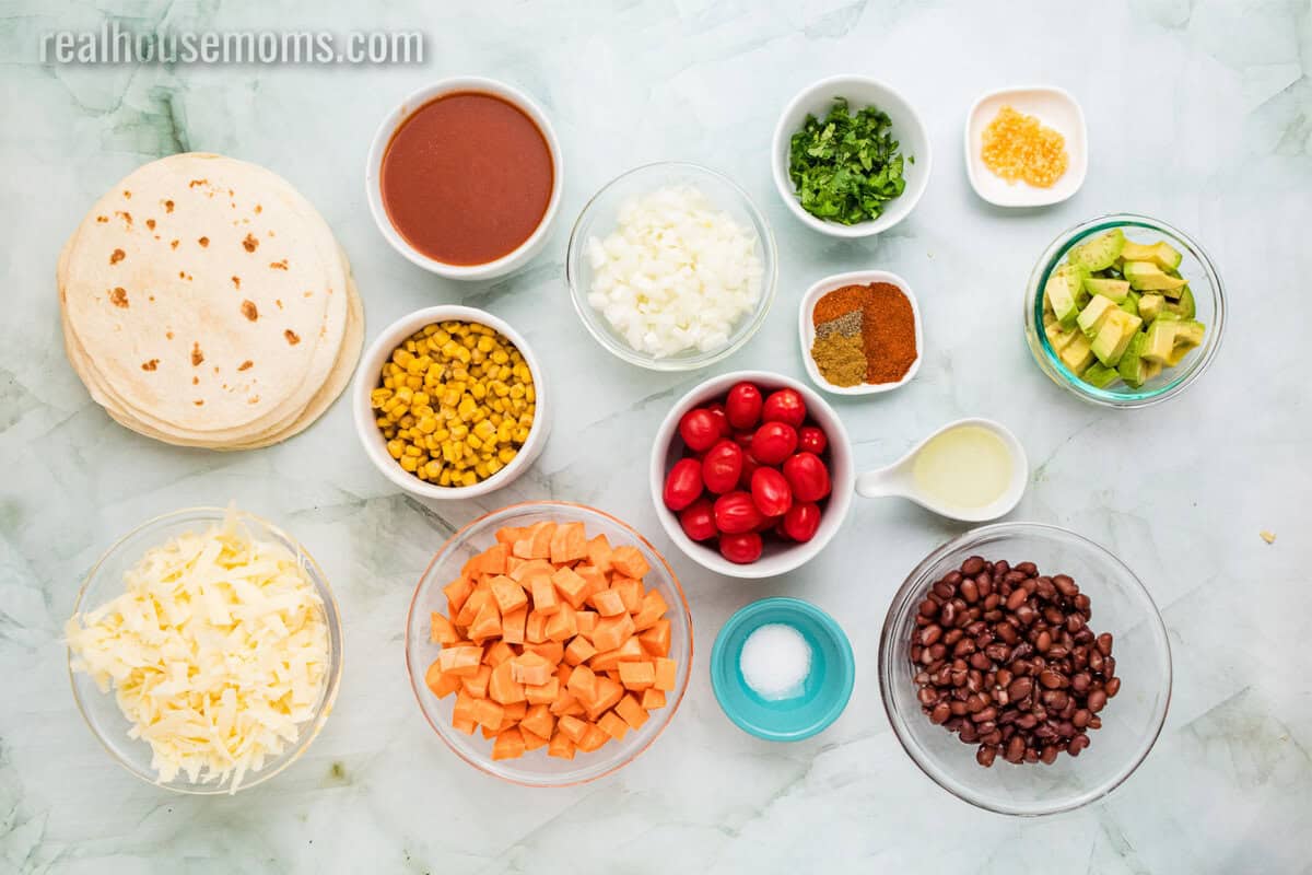 ingredients to make sweet potato black bean enchiladas in bowls on a counter