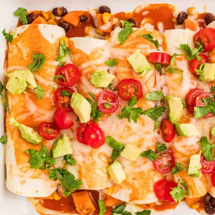 square image of sweet potato black bean enchiladas with a white baking dish