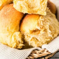 sweet potato dinner rolls piled in a basket with recipe name at the bottom