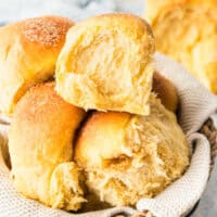 square image of sweet potato dinner rolls piled in a basket