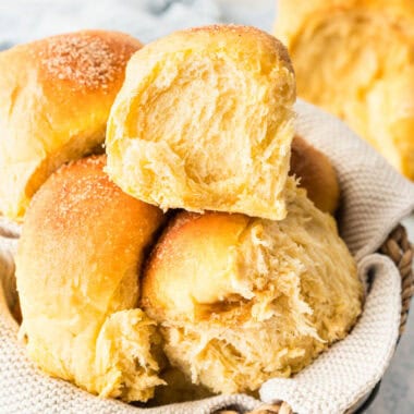 square image of sweet potato dinner rolls piled in a basket