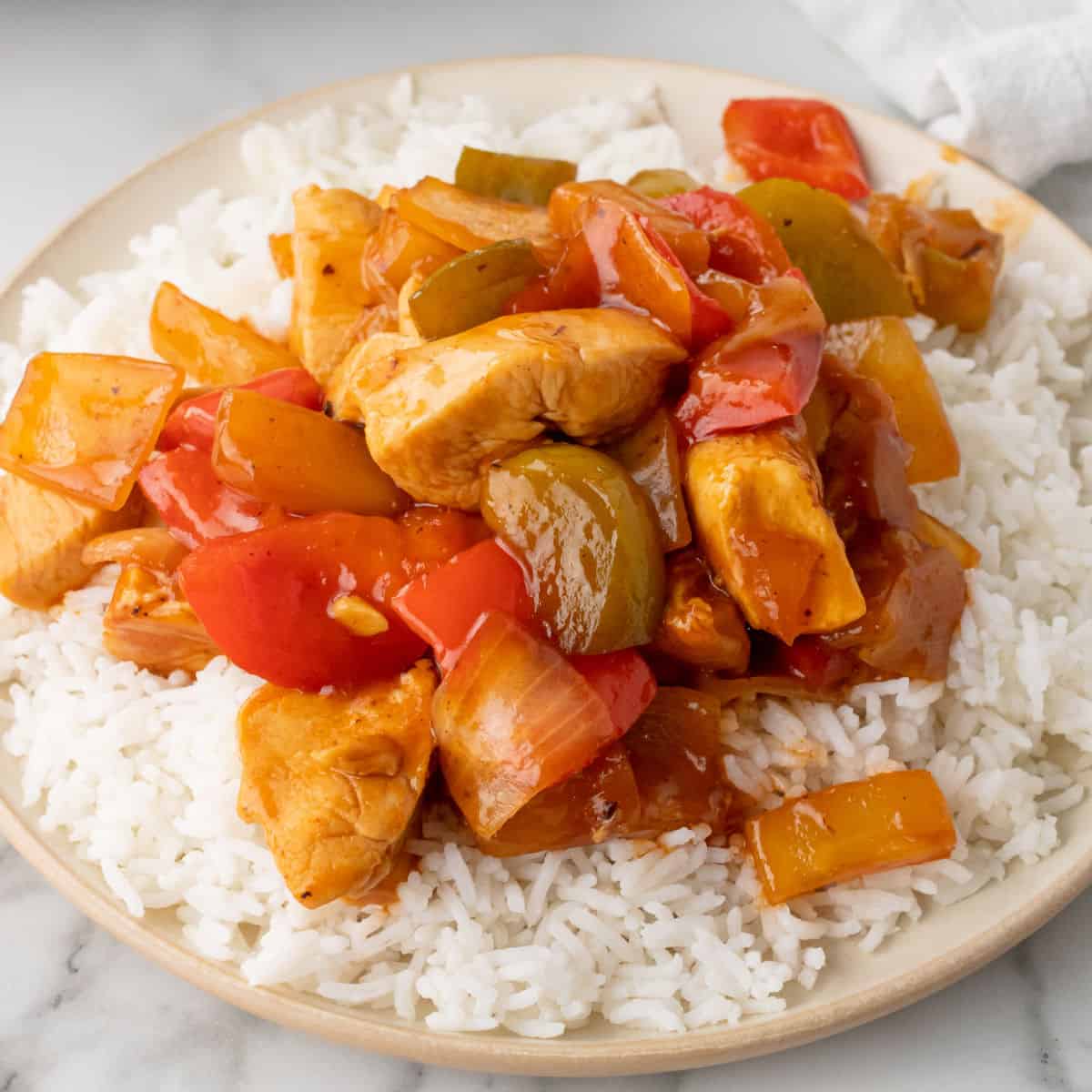 square image of sweet and sour chicken served over cooked white rice