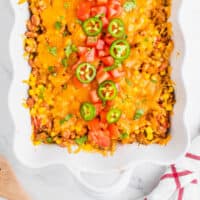taco casserole bake topped with diced tomatoes and jalapeno slices with recipe name at the bottom