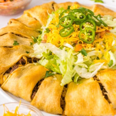 square image of taco crescent roll ring with lettuce, tomato, cheese, and jalapeno in the middle