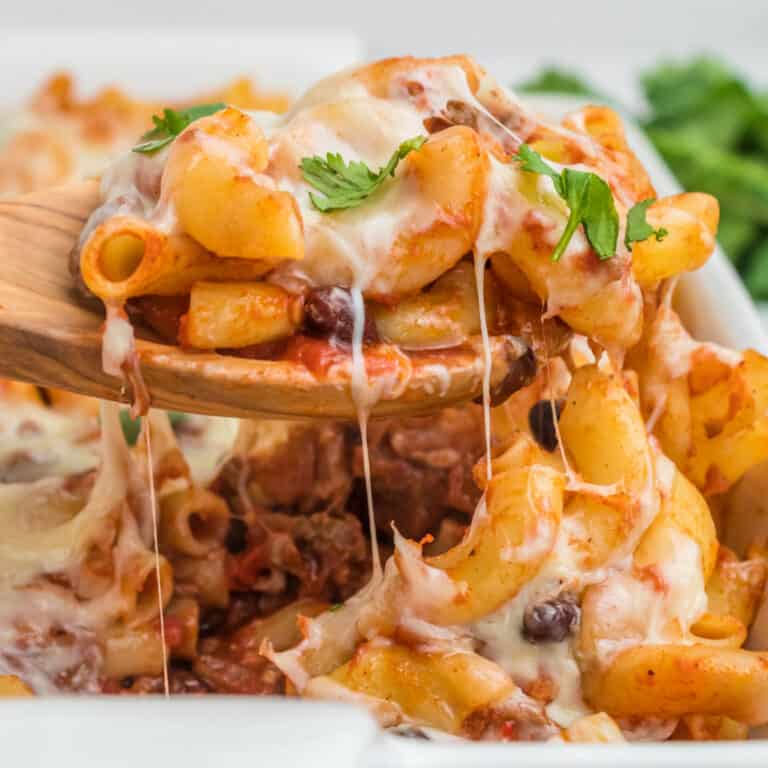 square image of a spoonful of taco mac and cheese pasta bake over the baking dish