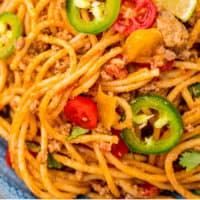 close up of taco spaghetti on a blue plate with recipe name at the bottom