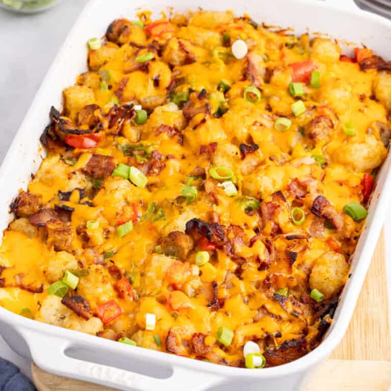 square image of tater tot breakfast casserole topped with sliced green onions in a baking dish