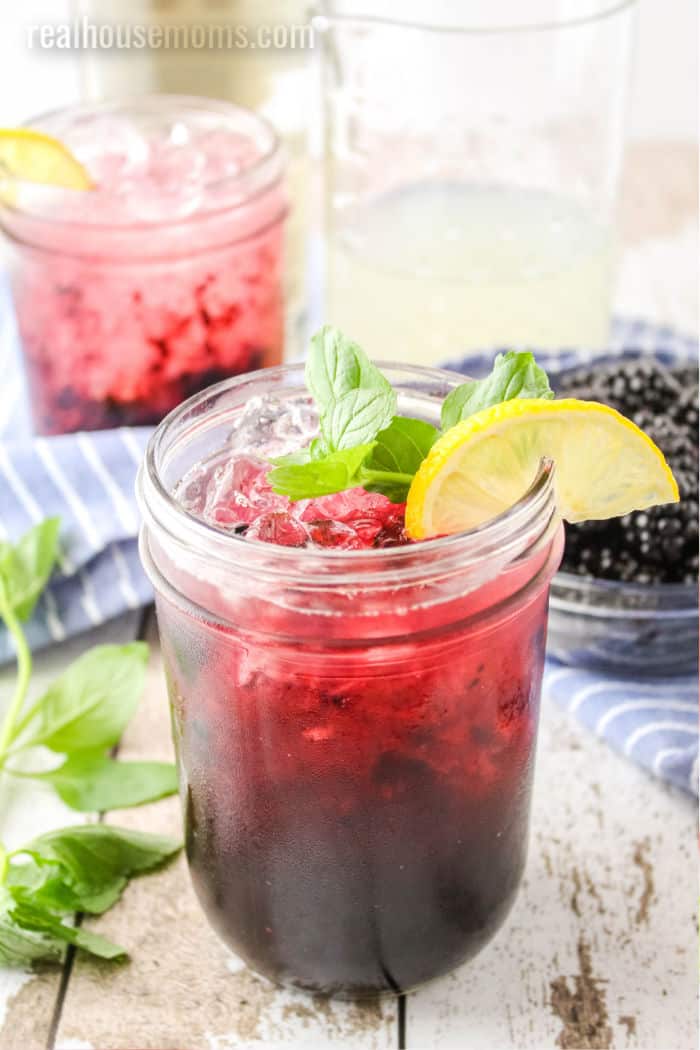 blackberry lemonade with tequila in mason jars garnished with lemon slices and mint
