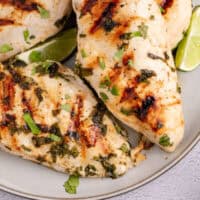 tequila lime grilled chicken on a plate with lime wedges with recipe name at the bottom