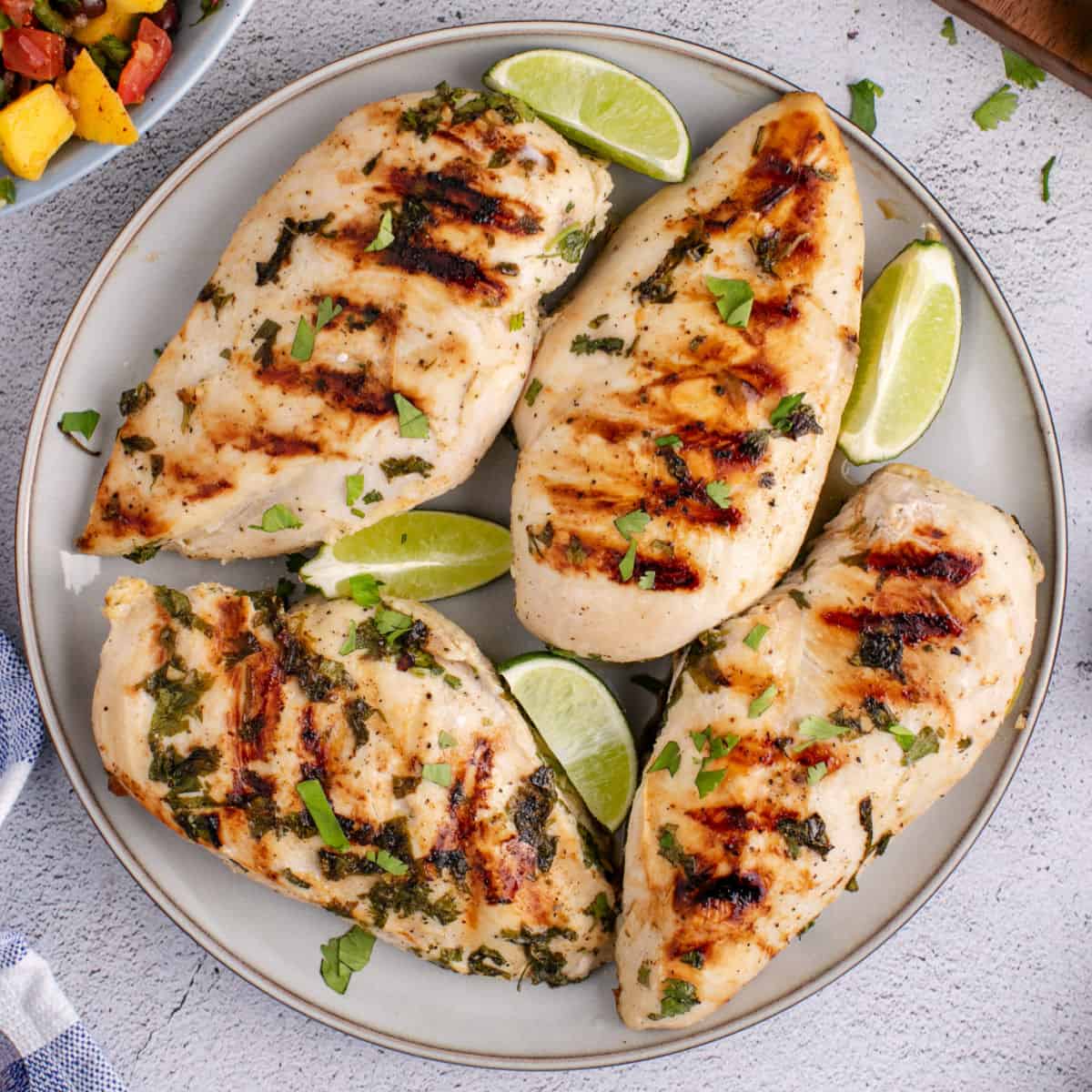 square image of tequila lime grilled chicken on a plate with lime wedges