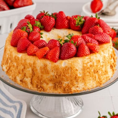 square image of angel food cake topped with strawberries on a cake stand
