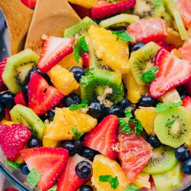 square close up image of the best fruit salad recipe topped with mint and brown sugar