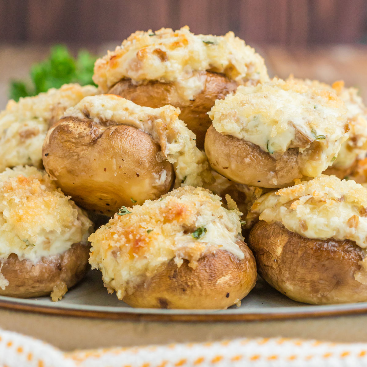 square image of three cheese stuffed mushrooms piled up on a plate