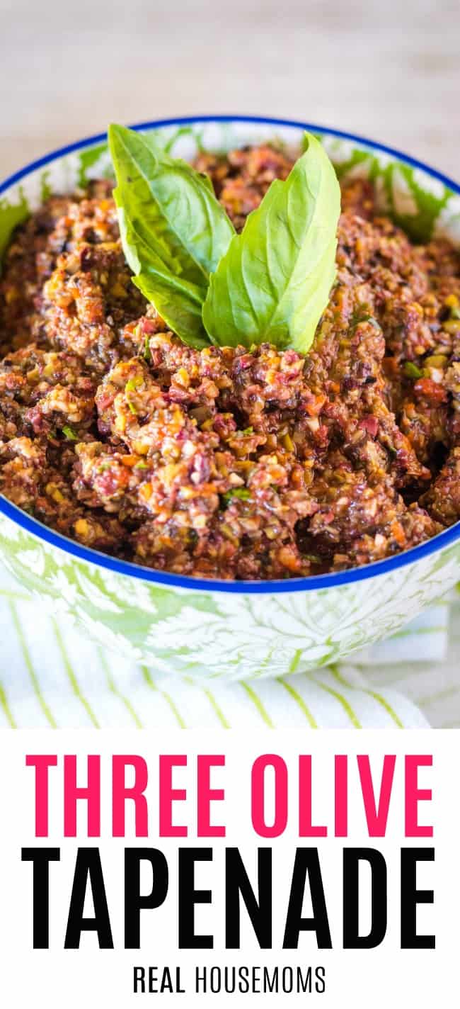three olive tapenade in a serving bowl with basil leaves for garnish