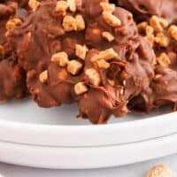 toffee peanut clusters piled on a plate with recipe name at the bottom