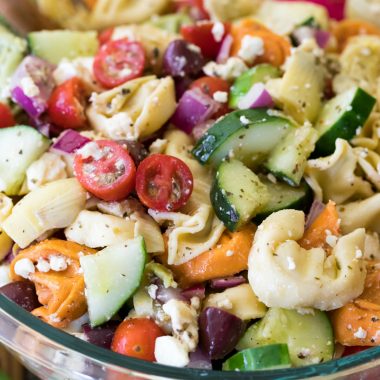Greek-style Tortellini Pasta Salad is loaded with colorful veggies and topped off with a zesty homemade dressing for a dish that's sure to be a hit at your next potluck or party!