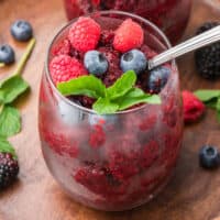 square image of triple berry wine slush in a glass with berries and mint on top for garnish