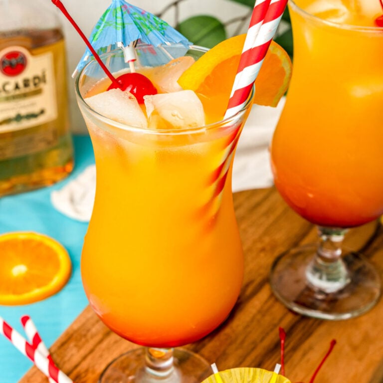square image of a tropical breeze cocktail with a cherry, orange slice, and cocktail umbrella