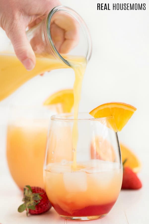 pouring orange juice into and glass to make tropical orange punch