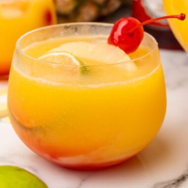 square image of a glass of tropical party punch with a cherry