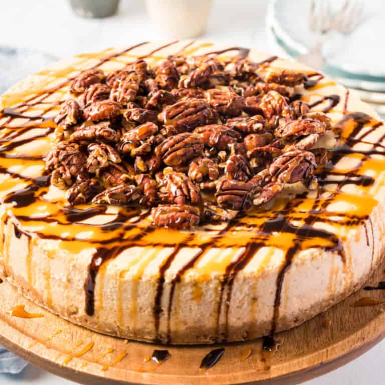 square image of turtle pumpkin cheesecake on a wooden cake stand