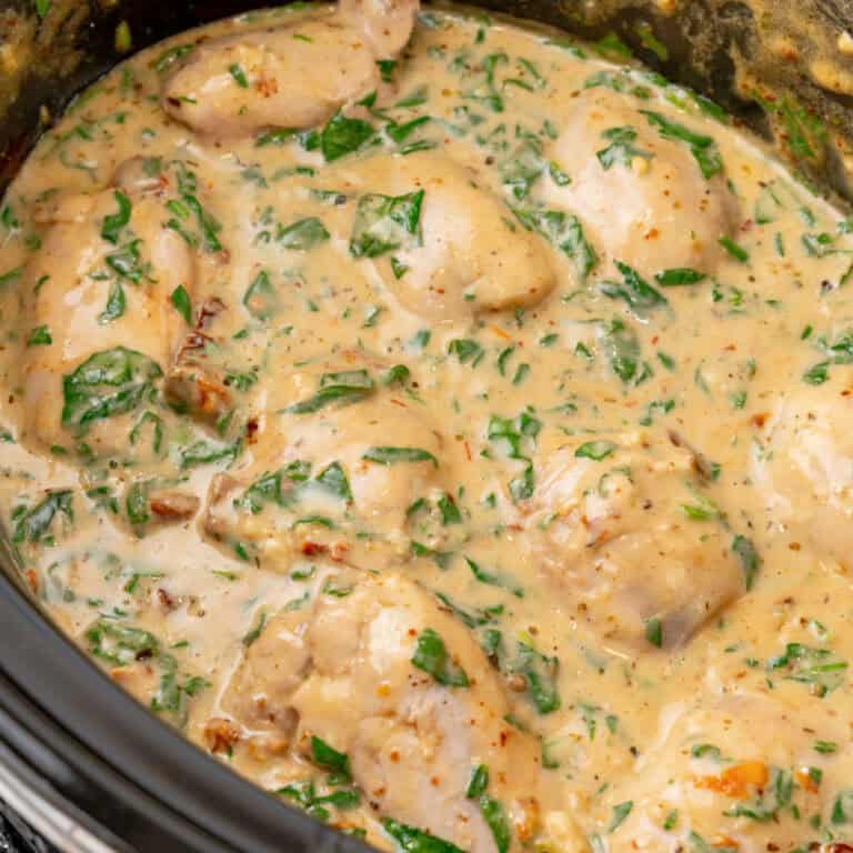square image of tuscan style crock pot chicken thighs in the slow cooker