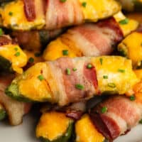 bacon wrapped jalapeno poppers with chives on a plate with recipe name at the bottom