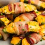 square image of bacon wrapped jalapeno poppers piled up on a plate