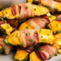 square image of bacon wrapped jalapeno poppers piled up on a plate