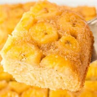 image slice of upside down banana cake on a cake server over the platter with the title of the post on top of the image in pink and black lettering