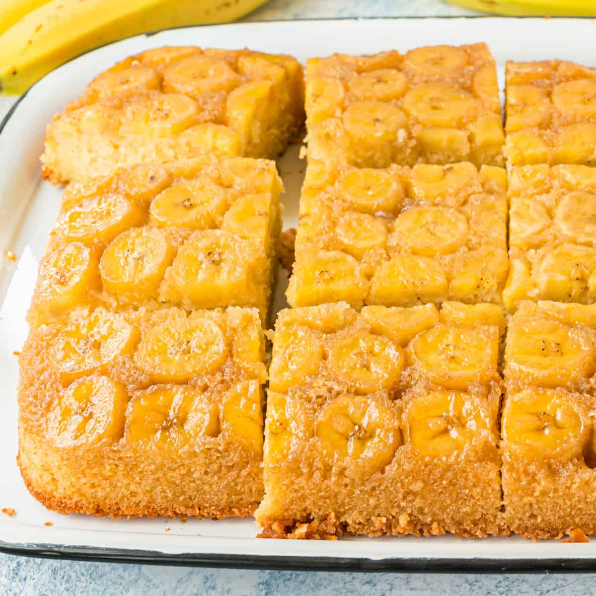 square image of upside down banana cake cut into slices on a serving platter