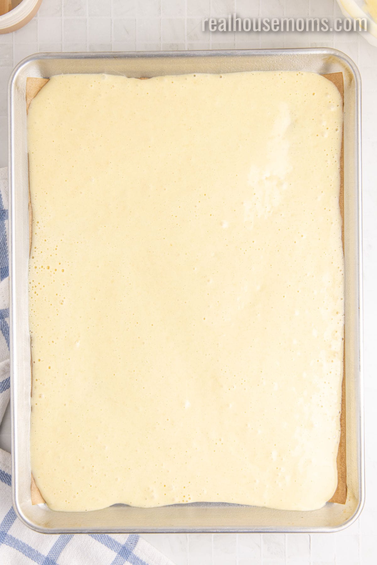 vanilla swiss roll cake batter pour into a parchment paper lined jelly roll pan