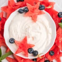 square image of a bowl of fruit dip surrounded by watermelon stars and blueberries