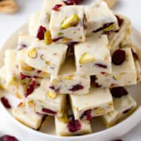 square image of cranberry pistachio fudge piled up on a plate