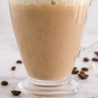 side view of a white chocolate mocha latter in a glass mug with recipe name at bottom