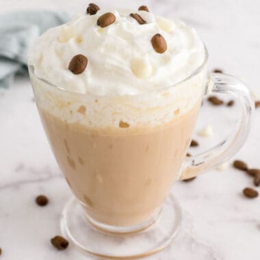 square image of white chocolate mocha latte in a glass coffee mug with whipped cram on top