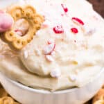 square image of White Chocolate Peppermint Cheesecake Dip with a cookie being dipped in