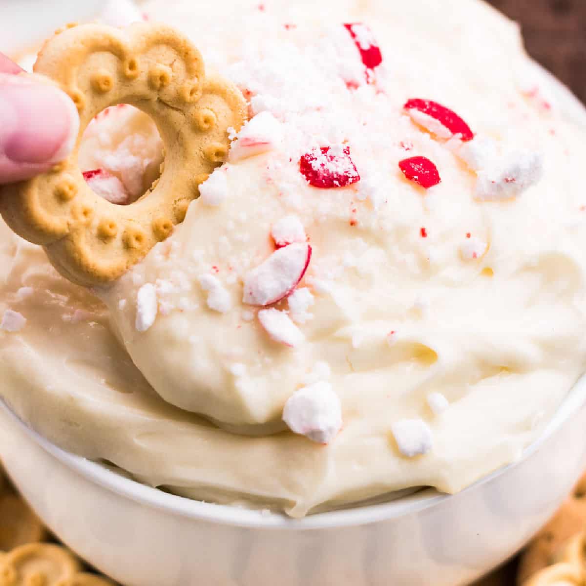 firkantet billede af hvid chokolade pebermynte Cheesecake Dip med en cookie bliver dyppet i