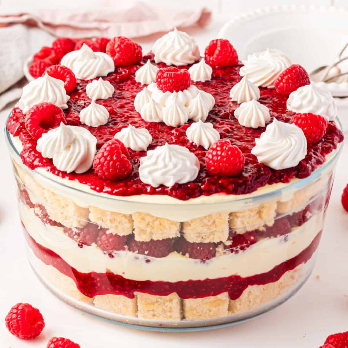 square image of a white chocolate raspberry trifle with whipped cream and fresh raspberries on top