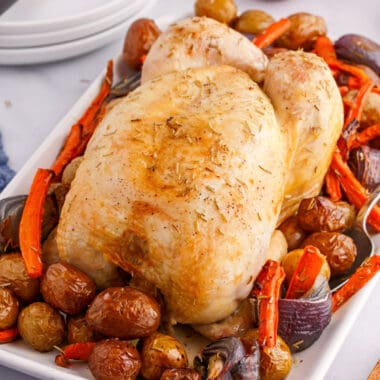 square image of whole roasted chicken and veggies on a platter