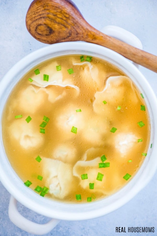 wonton soup in a pot with a wooden serving spoon