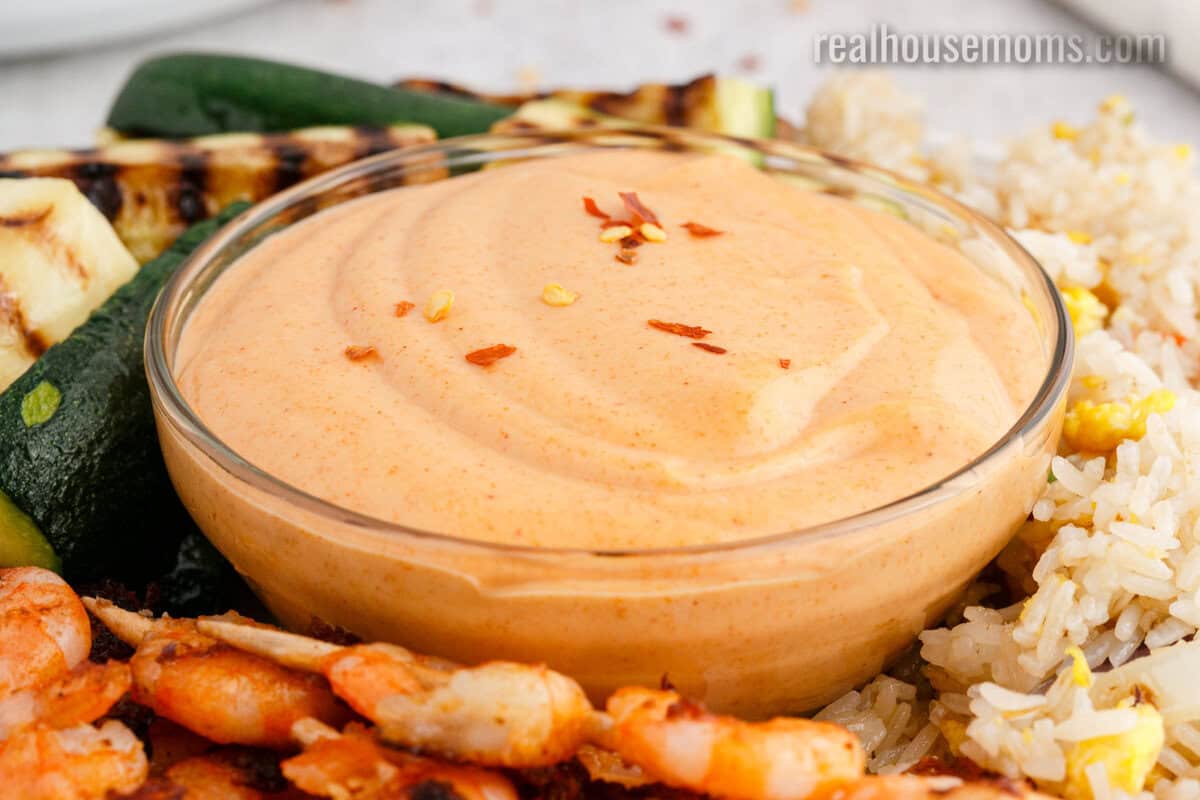 angled view of yum yum sauce topped with red pepper flakes in a glass bowl