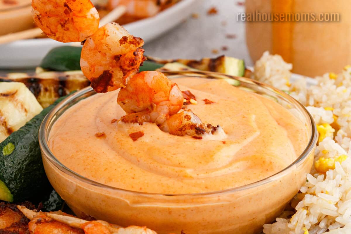 shrimp skewer being dipped into a bowl of yum yum sauce