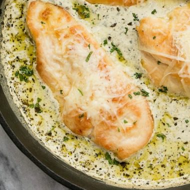 CREAMY SKILLET PESTO CHICKEN has the most flavorful white cream pesto sauce imaginable covering juicy chicken, and topped with parmesan cheese!