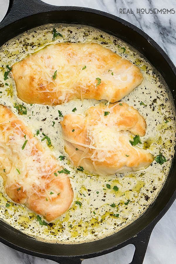 Creamy Skillet Pesto Chicken in a cast iron skillet surrounded by sauce, ready to serve