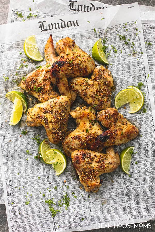 Jerk Chicken Wings piled up on newspaper with lime wedges for serving