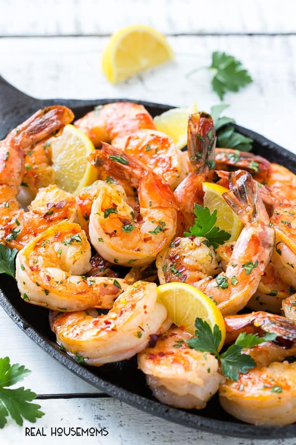 spicy garlic shrimp on a serving platter with lemon wedges and parsley