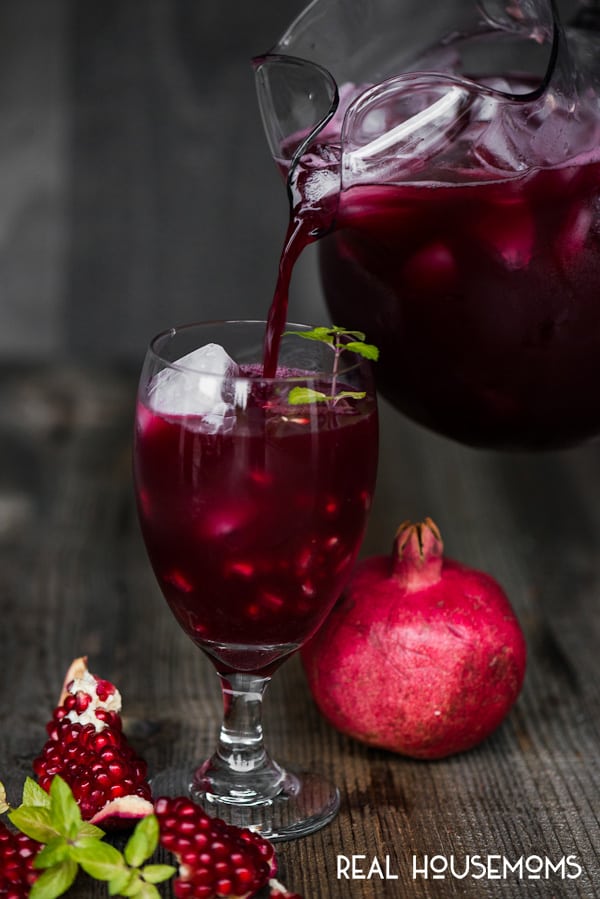 Spiked Pomegranate Punch being poured into a glass filled with ice