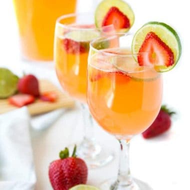 Strawberry & Lime Moscato Punch poured into wine glasses and garnished with strawberry and lime slices