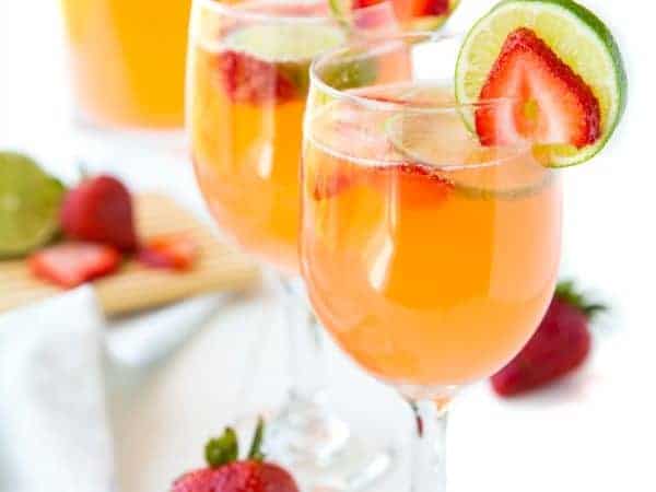 Strawberry & Lime Moscato Punch poured into wine glasses and garnished with strawberry and lime slices